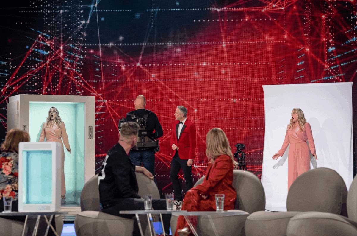 A Holobox on a television studio floor: a presenter appears life size inside the display while the show goes on beside it.